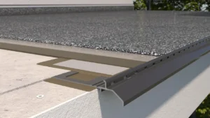 Zbliżenie na profil okapowy K20 zamontowany na krawędzi balkonu z posadzką żywiczną typu kamienny dywan, widoczna hydroizolacja i podkład cementowy.