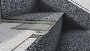 Zbliżenie na krawędź stopnia z posadzką żywiczną typu kamienny dywan, pokazujące profil schodowy i estetyczne wykończenie powierzchni.