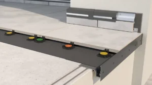 Zbliżenie na krawędź tarasu wentylowanego z płytami ceramicznymi ułożonymi na regulowanych wspornikach, widoczny profil okapowy oraz warstwa izolacyjna pod płytami.