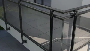 Balustrada szklana z czarnymi aluminiowymi słupkami i uchwytami, montowana na krawędzi tarasu, widok z bliska.
